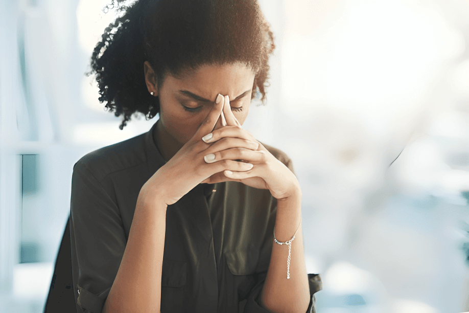 A woman, appearing to be of African descent, looks stressed.