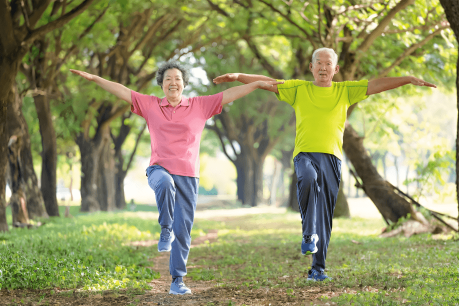 Two older adults doing tai chi in a park setting.