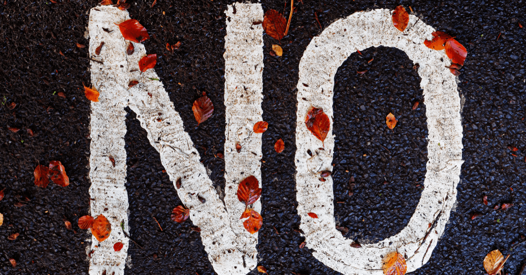 The word "NO" painted on asphalt with autumn leaves.