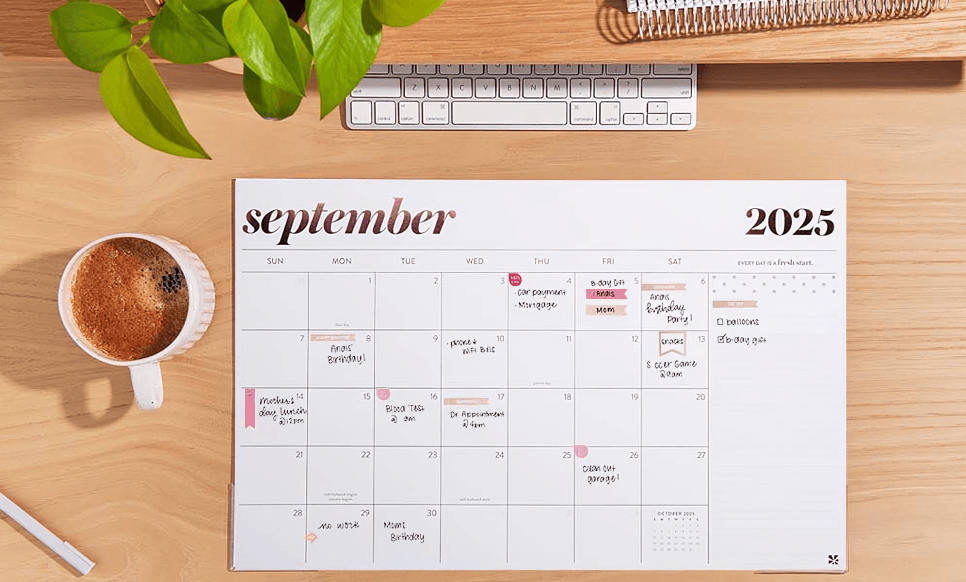 September 2025 calendar on desk with keyboard and coffee.