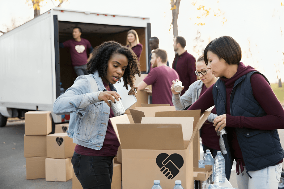 Volunteers packing donation boxes near a moving truck.