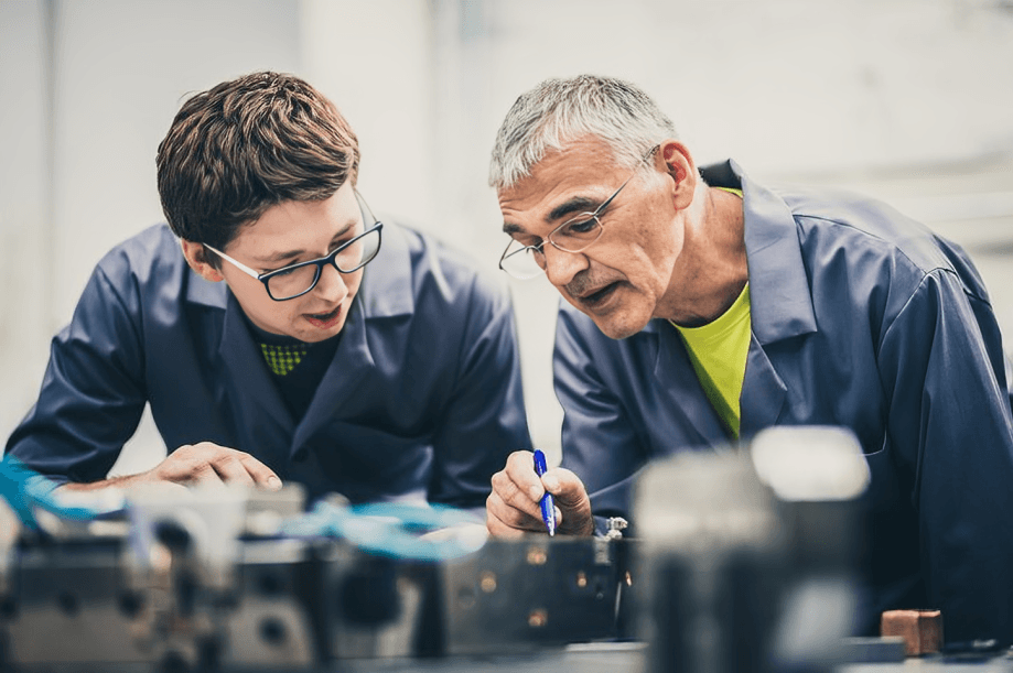 Two male engineers collaborating intently on a machine.