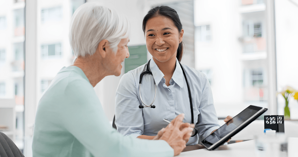 A friendly female doctor smiling at an elderly patient.