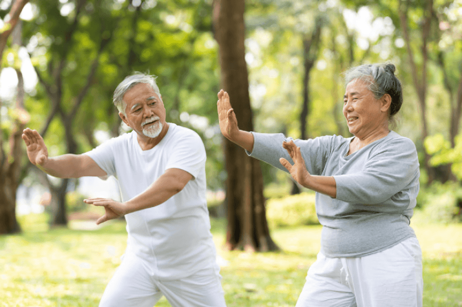 Two older adults doing tai chi outdoors.