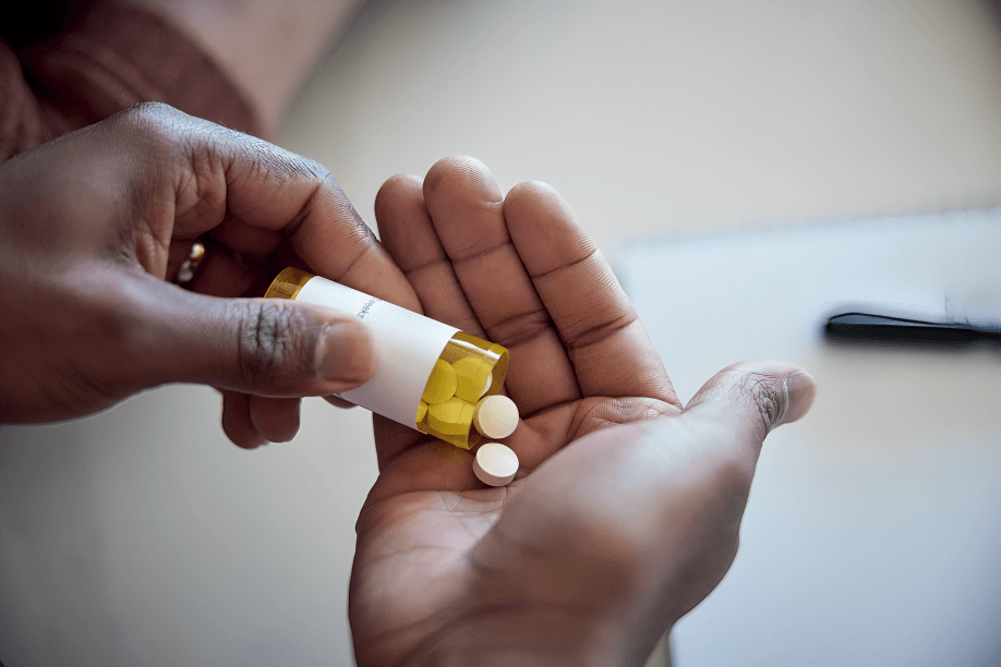 Hands pour pills from the bottle into the palm.