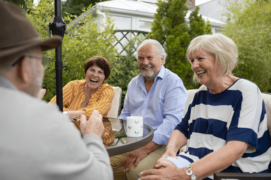 Four seniors happily socializing on an outdoor patio.