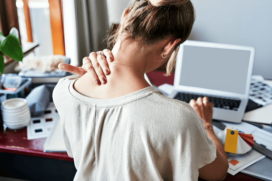 The woman at the desk with the laptop rubs her neck.