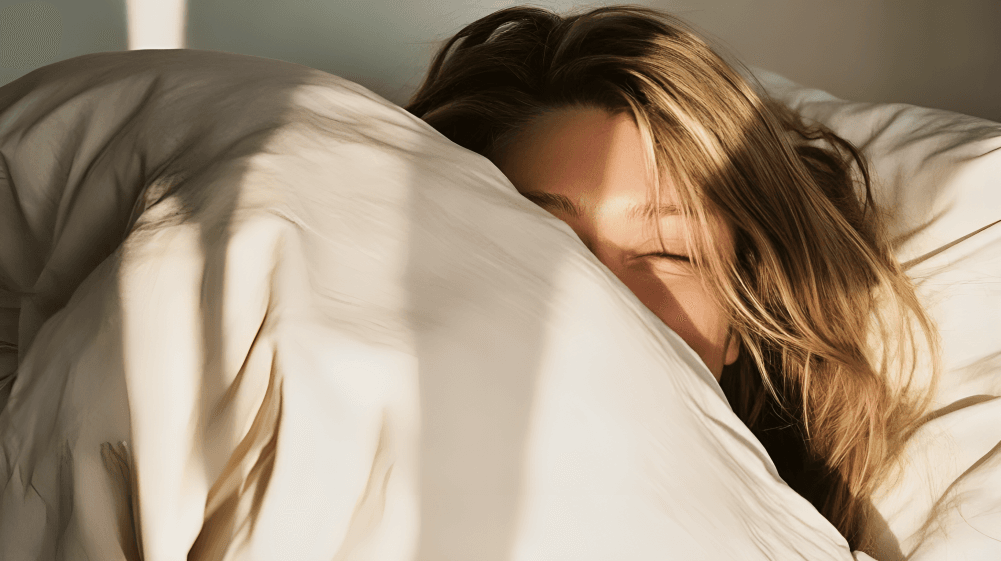 Woman peeking from under the covers in bed.