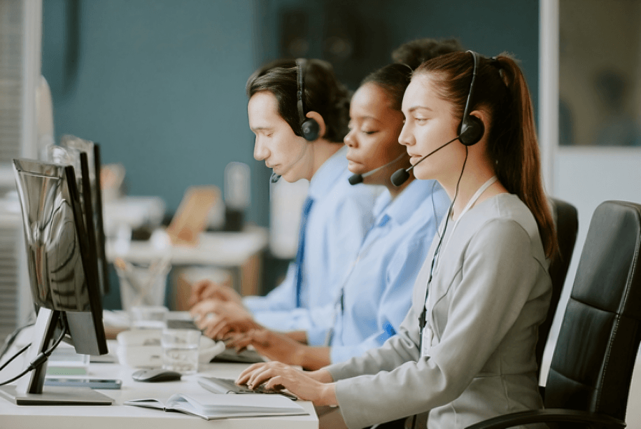 Three call center agents working at computers.