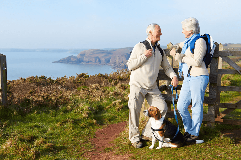 Senior couple and dog enjoying coastal walk views.