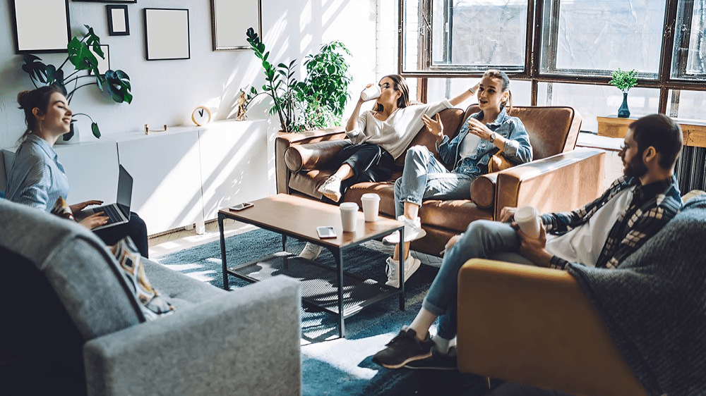 A group of people relaxing on a couch in a living room.