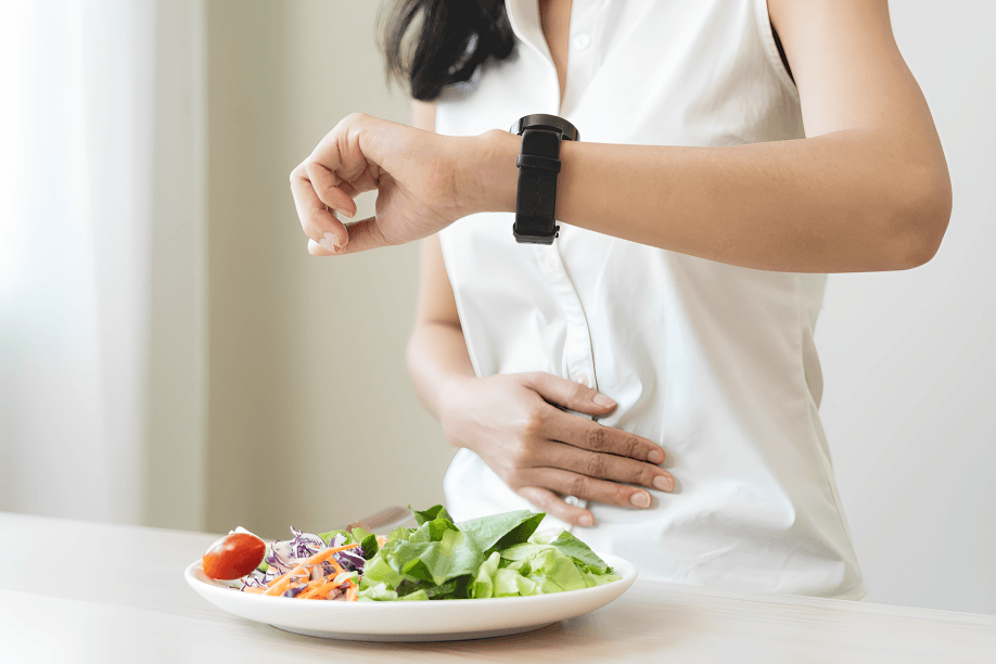 Woman checking watch before eating salad, timing her meal.