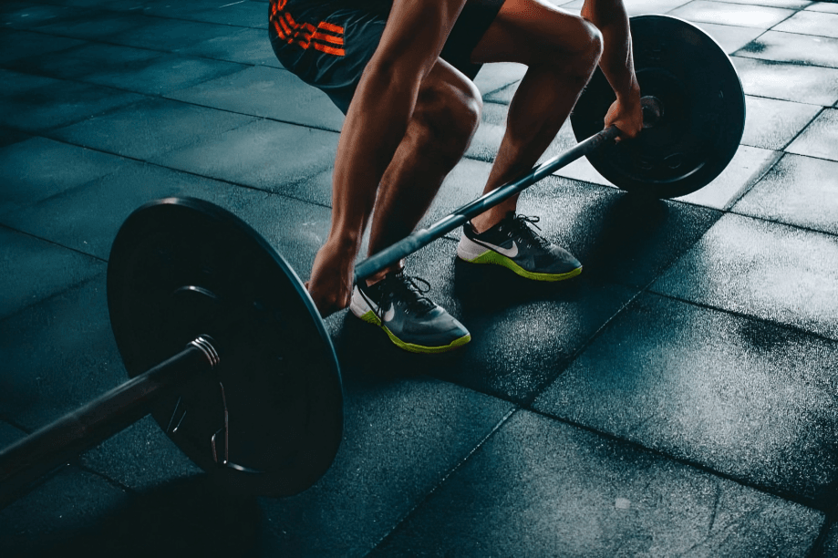 Man deadlifting a barbell in a gym.