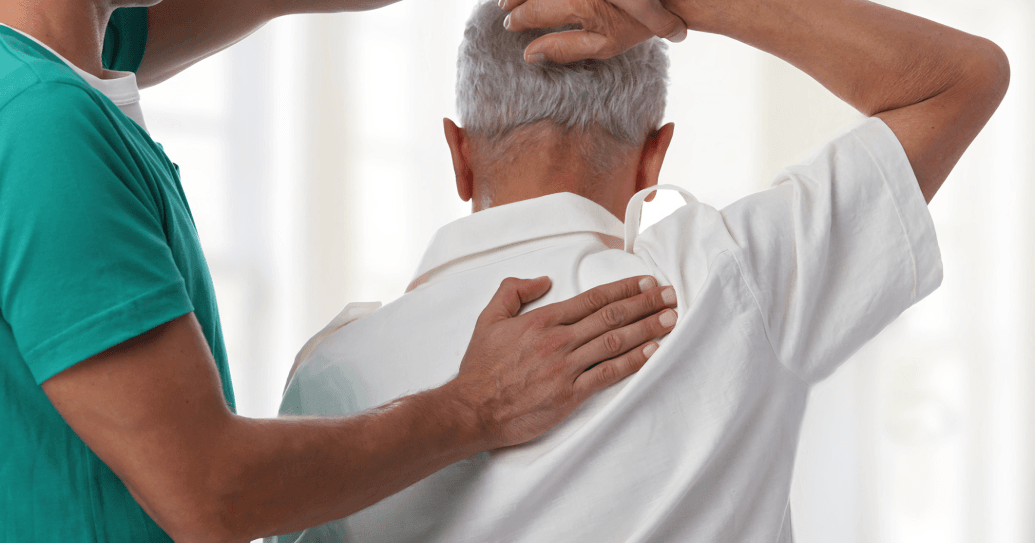 A therapist assisting a senior man with shoulder exercise.