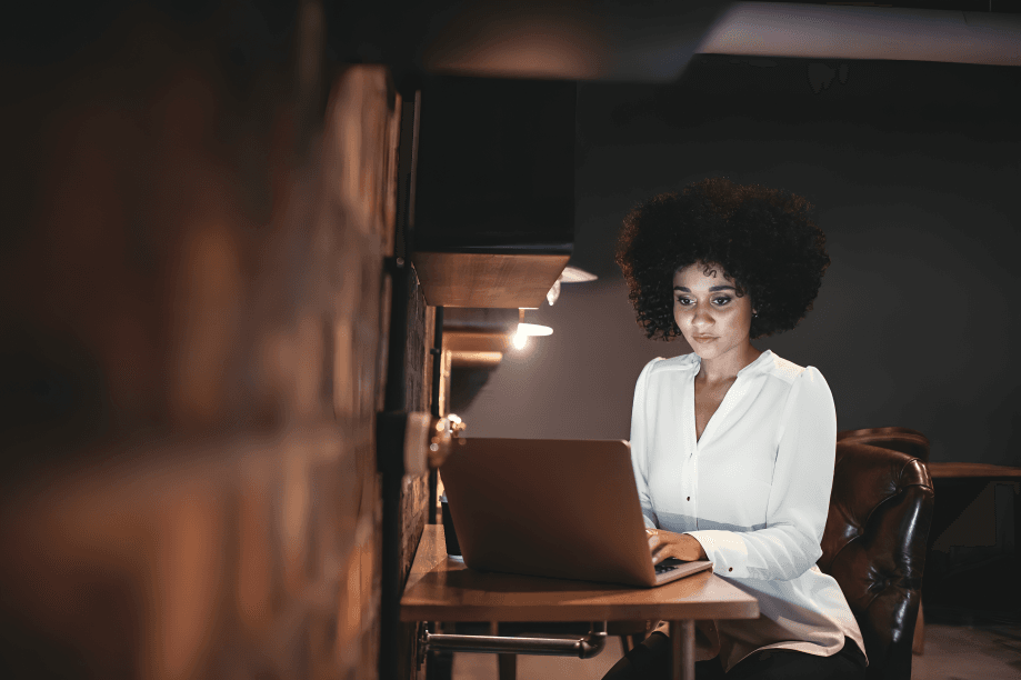 Woman, appearing to be of African descent, works on laptop.