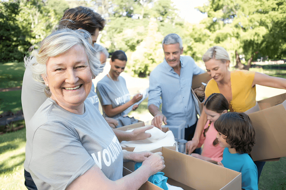 Smiling diverse volunteers packing boxes outdoors in a park.