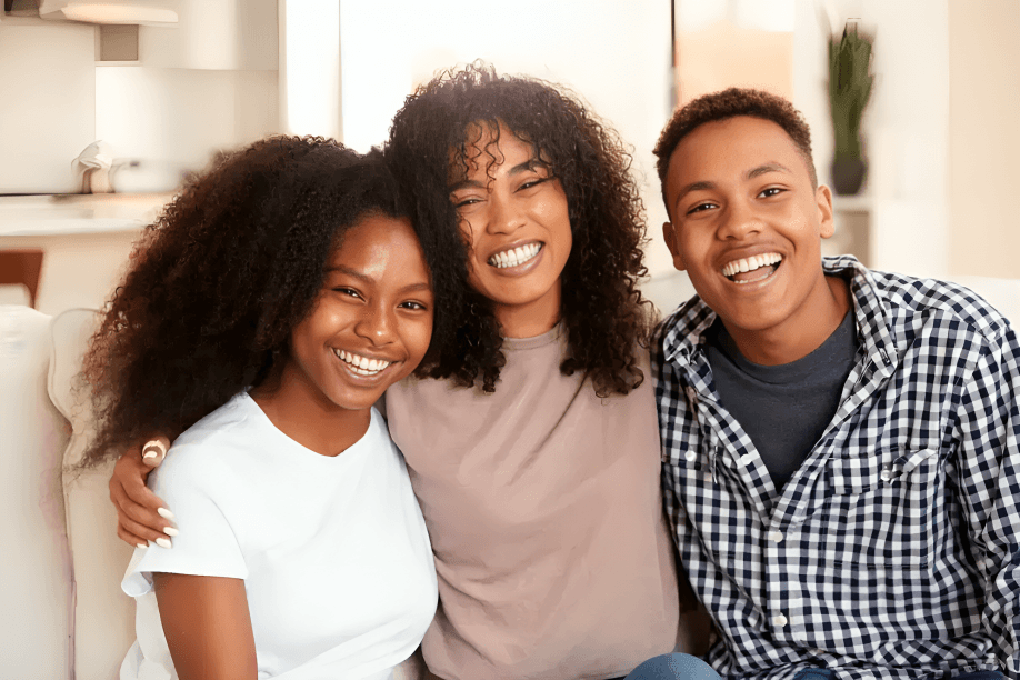 Three young people, smiling and embracing.