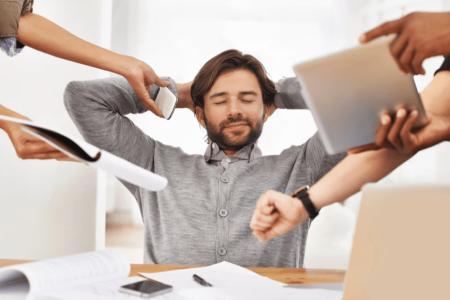 Calm man surrounded by demanding hands and devices.
