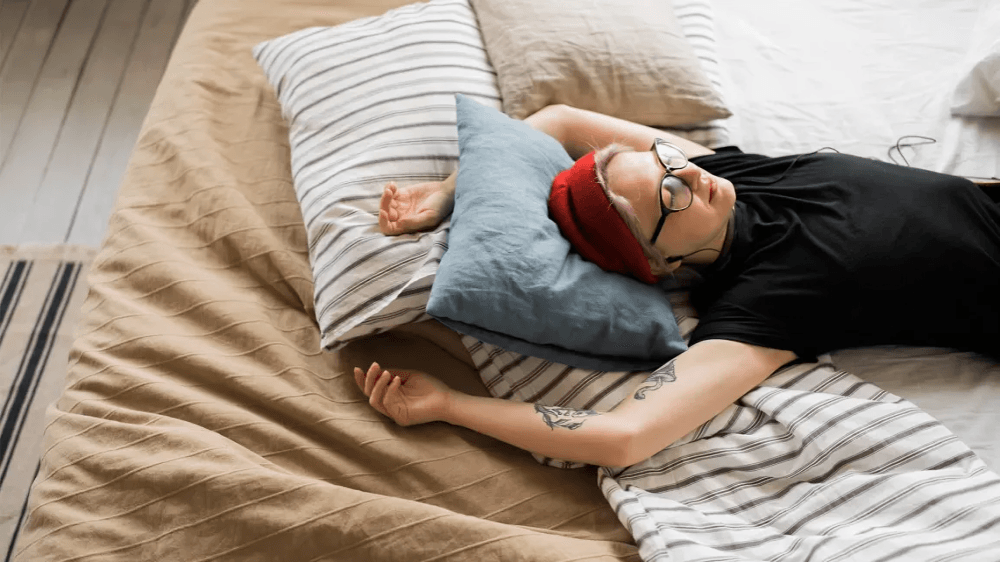 Person sleeping with headphones and a red beanie.