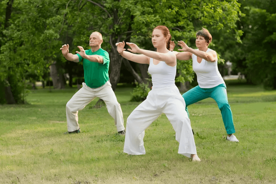 Three people possibly practice Tai Chi in a park.