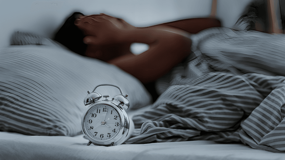 Man in bed annoyed by a ringing alarm clock.