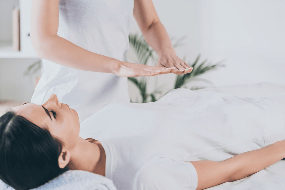 Practitioner's hands hovering over a woman's torso during reiki.