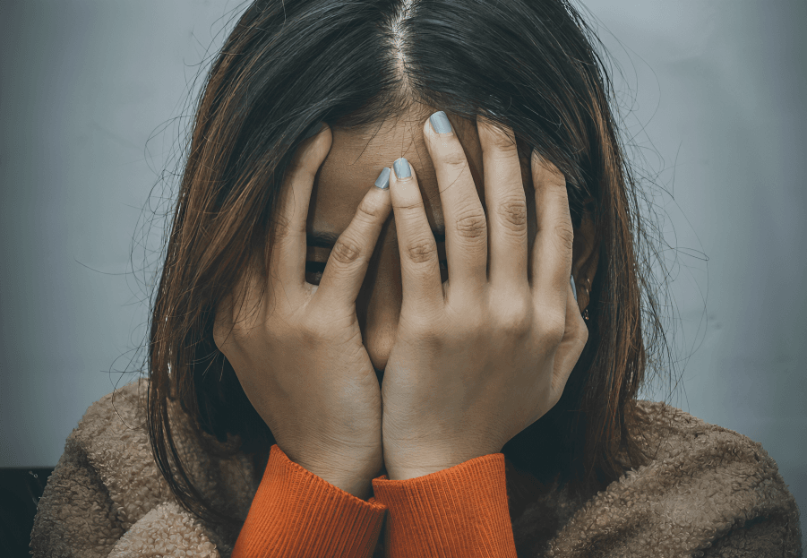 Person covering face with hands, appearing distressed.