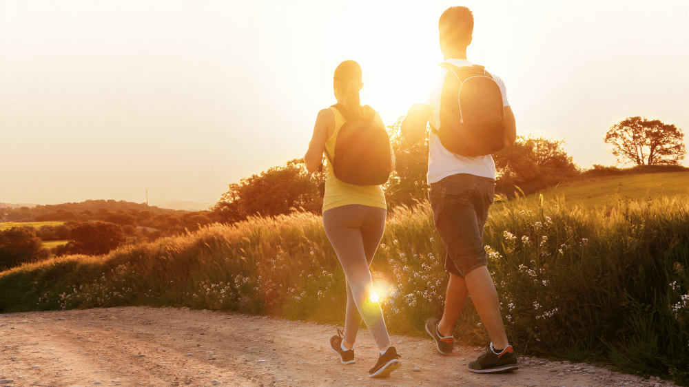 Two people walking on a path at sunset.