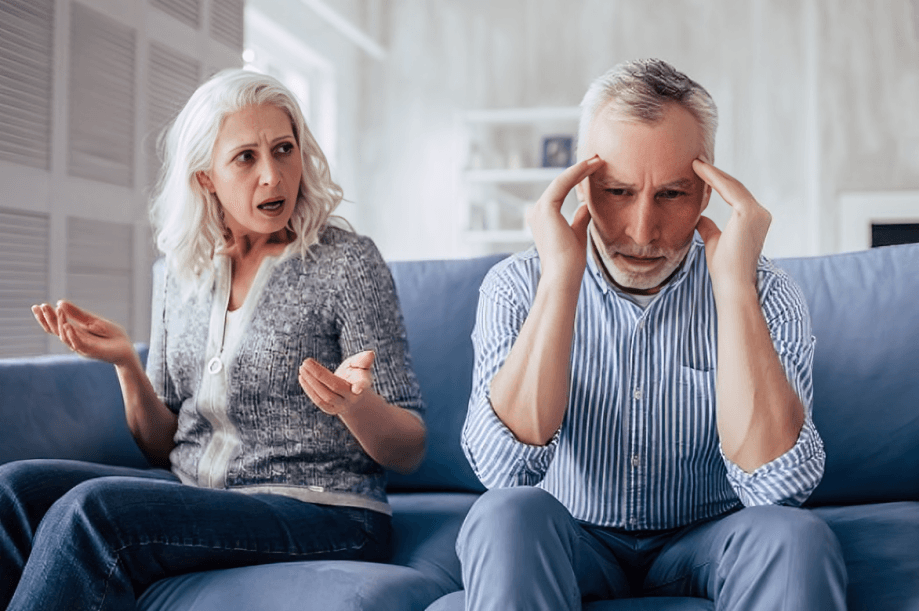 Couple on couch, woman arguing, man stressed.