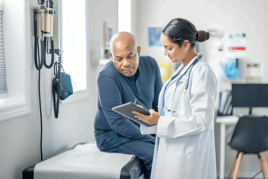 A doctor shows a tablet to a male patient.