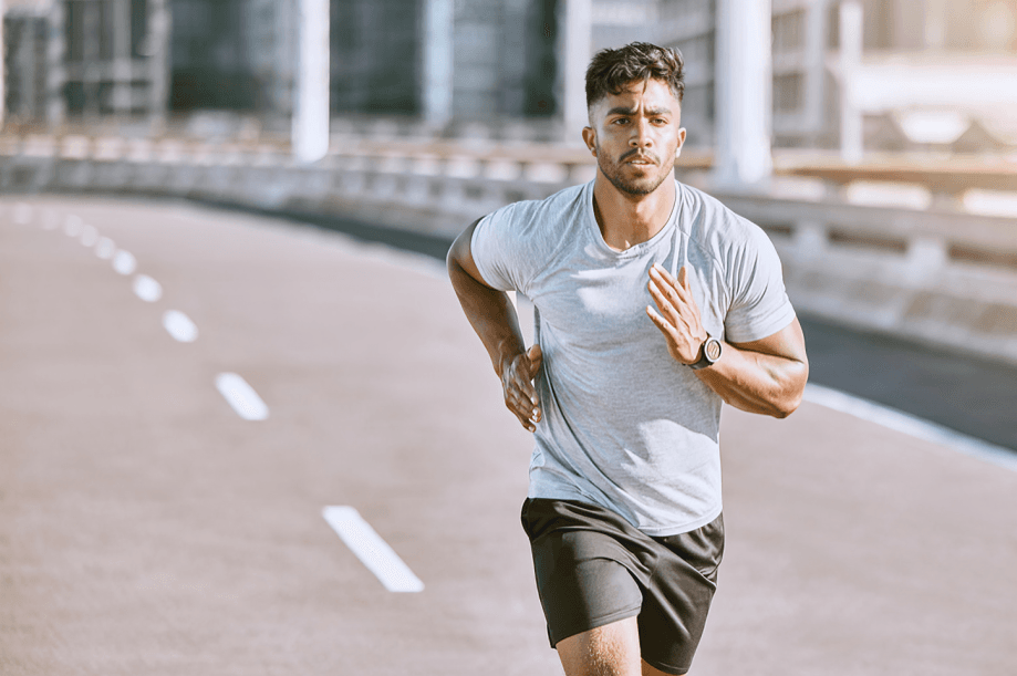 A fit man running outdoors on a sunny day.